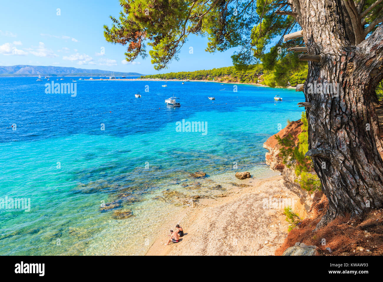 Unidentified giovane della gente seduta sulla spiaggia vicino al famoso capo di Zlatni Rat nella città di Bol, isola di Brac, Croazia Foto Stock