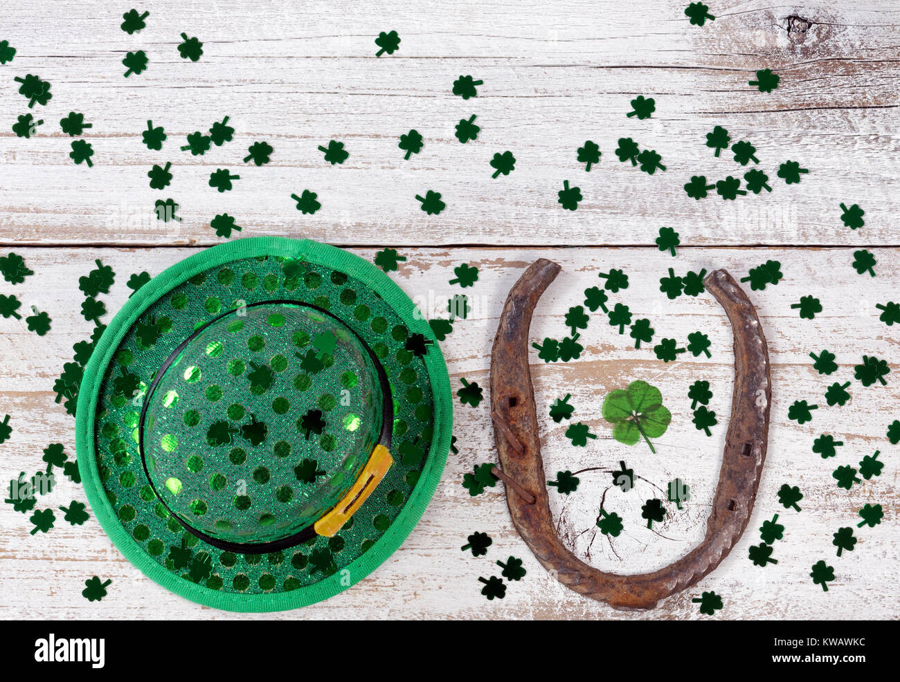 Real quattro leaf clover nel mezzo del ferro di cavallo arrugginito con hat e trifogli lucido su rustiche tavole in legno in vista aerea Foto Stock