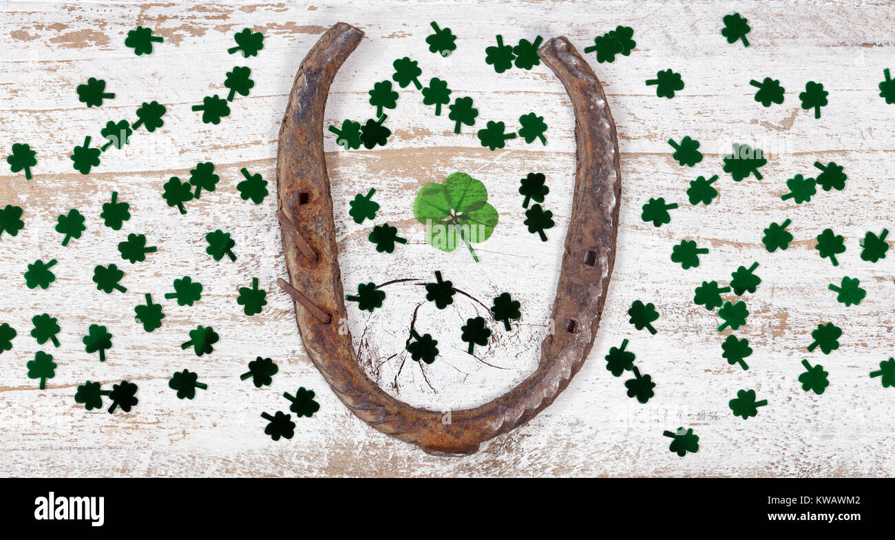 Real quattro leaf clover nel mezzo del ferro di cavallo arrugginito e trifogli lucido su rustiche tavole in legno in vista aerea Foto Stock