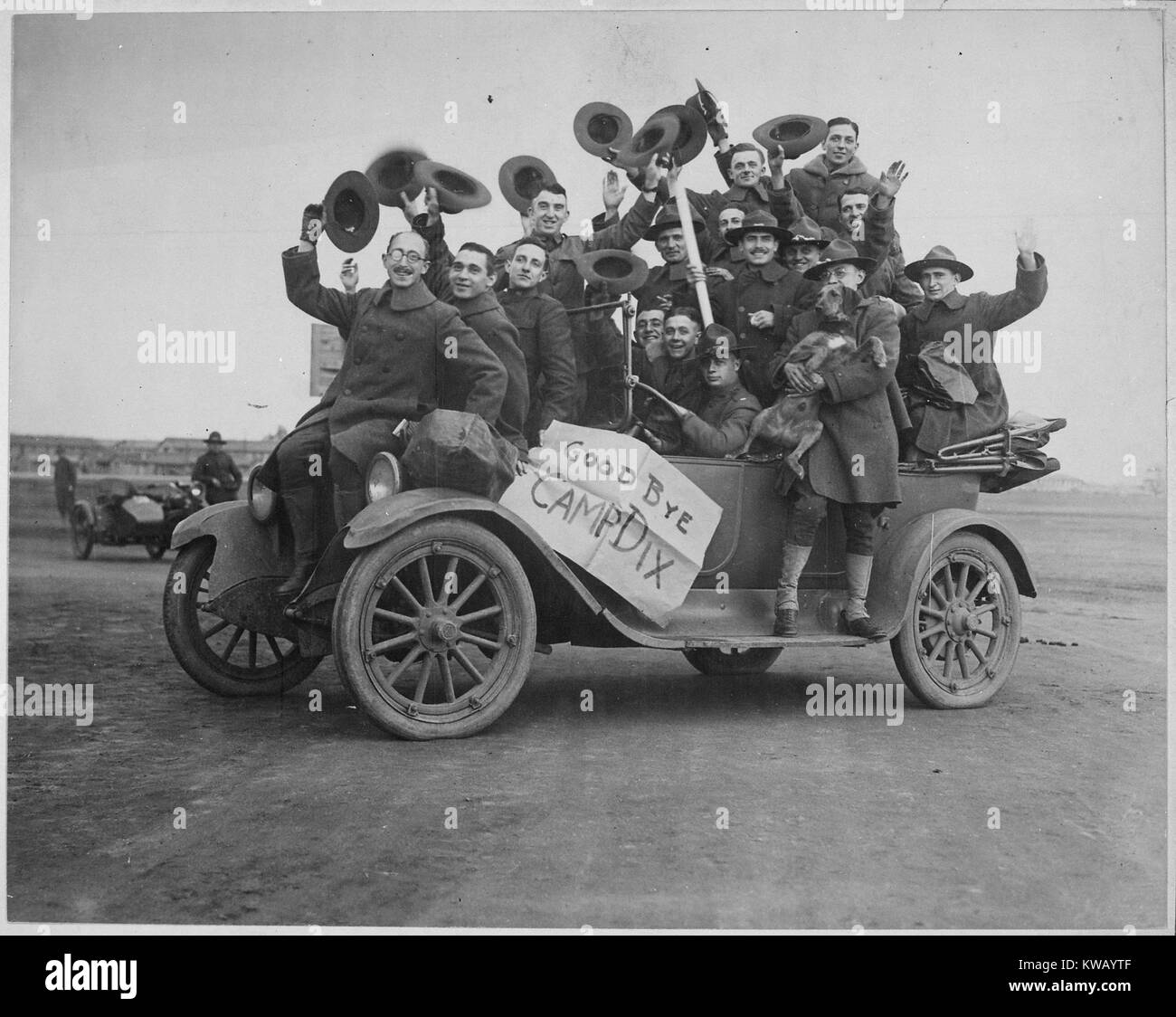 Una dozzina di soldati USA, indossano uniformi con lana di cappotti e cappelli di sollevamento verso l'aria, il sorriso e la forma d'onda impilati in una macchina sul loro modo di Camp Dix, con un segno di cartone che legge 'addio Camp Dix, ' New Jersey, 1917. Immagine cortesia archivi nazionali. Foto Stock