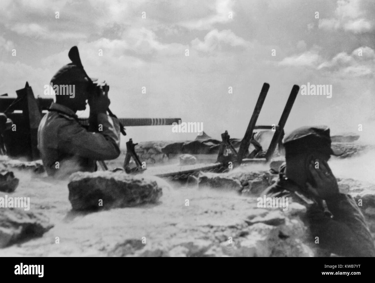 Truppe tedesche nel nord deserto africano durante l offensiva britannica. Due soldati sono in una forma a zig-zag trincea, uno osservando con il binocolo, un'altra schermatura le sue orecchie da un esplosione di artiglieria. Nov. 21-30, 1941. Guerra mondiale 2. (BSLOC 2014 10 3) Foto Stock