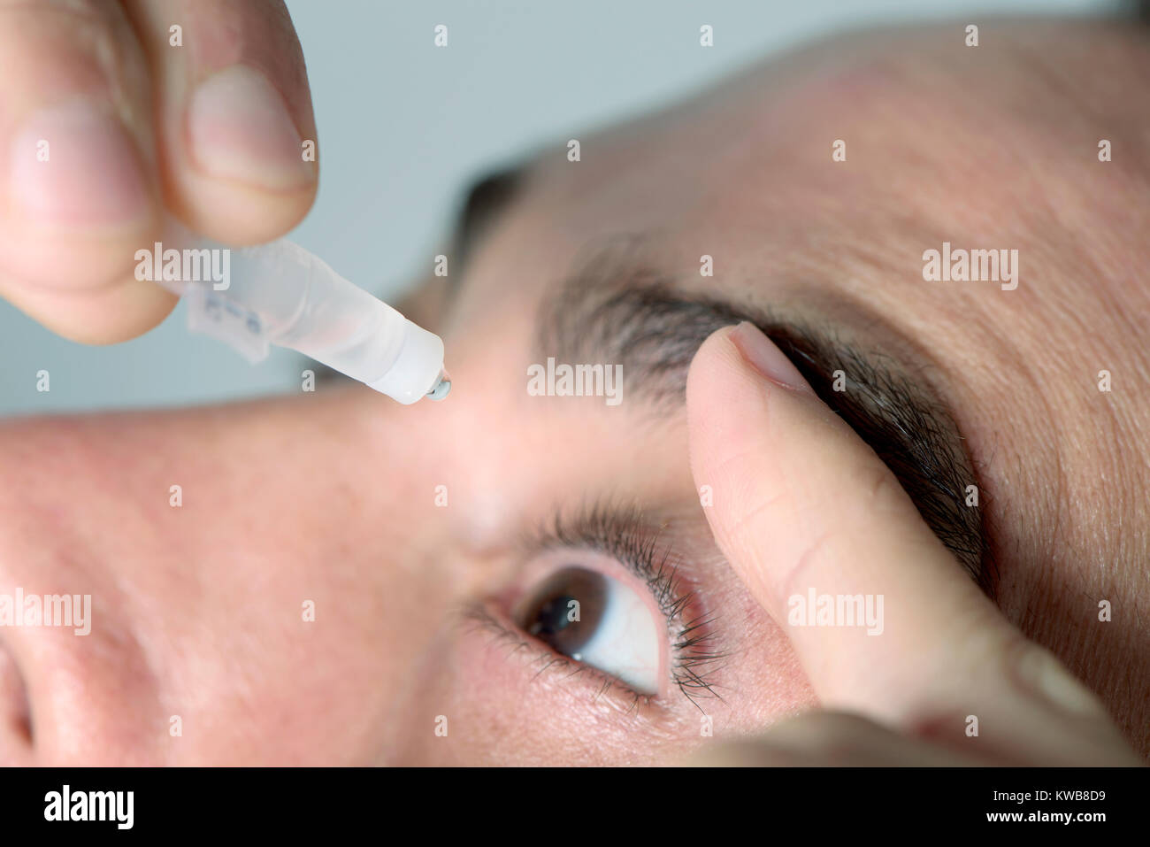 Closuep di un giovane uomo caucasico applicando occhio gocce per gli occhi Foto Stock