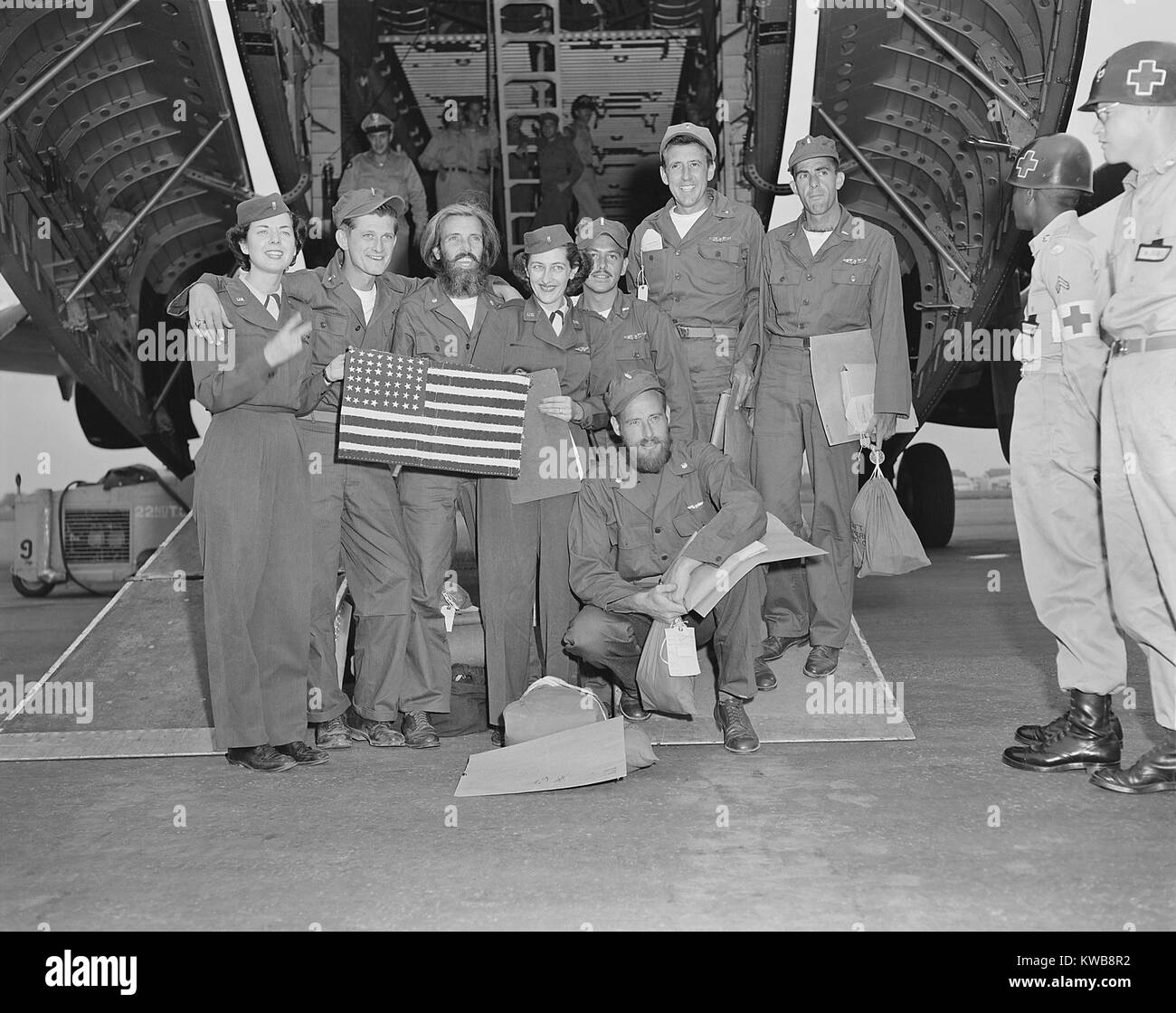 Liberati i prigionieri di guerra, un B-29 equipaggio posano con il loro volo infermieri a Tachikawa Air Base, Giappone. Hanno fatto la bandiera americana durante 33 mesi in un nord coreano POW Camp. Il loro B-29 è stato il primo ad essere abbattuto da un MiG fighter nella guerra coreana. Ca. July-Aug. 1953. (BSLOC 2014 11 175) Foto Stock