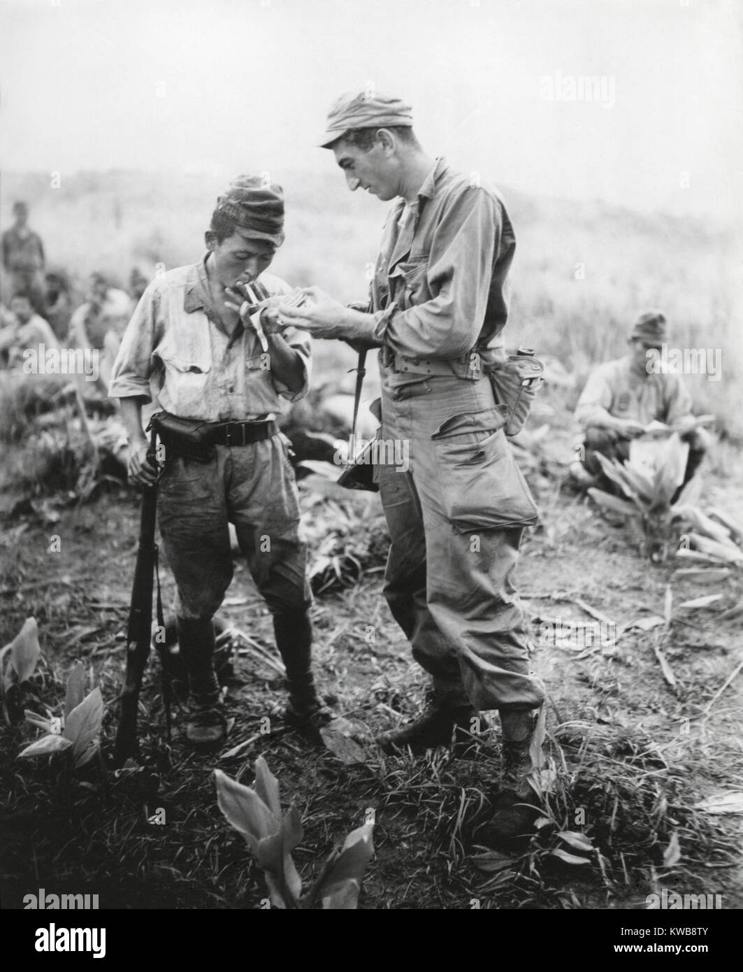 Soldato nordamericano di luci una sigaretta per un ex nemico di protezione. Essi sono a una conferenza di riscatto tra americani e giapponesi ufficiali su un Sierra Madre Mountain top nel nord di Luzon, Filippine. Agosto 22, 1945. Guerra mondiale 2. (BSLOC 2014 10 128) Foto Stock