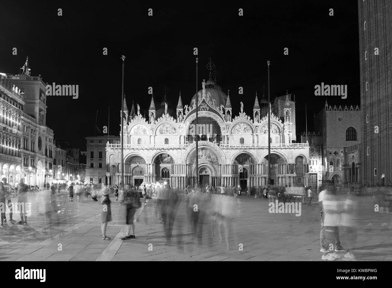 Movimento sfocate immagini di persone a piedi di piazza San Marco (Piazza San Marco) durante la notte con il famoso punto di riferimento basilica in background. Foto Stock