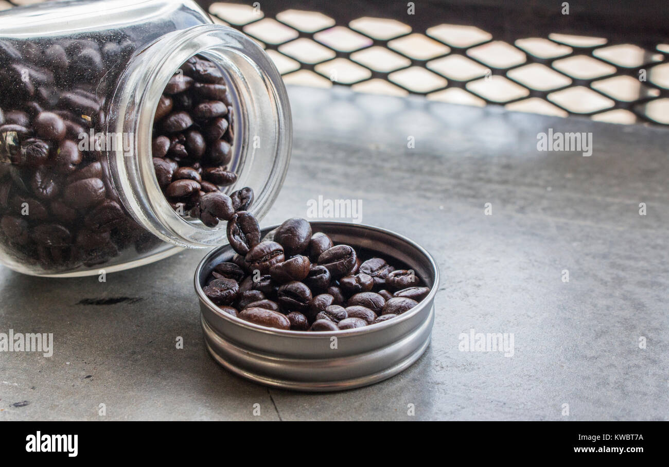 Close up di chicchi di caffè nel tappo della bottiglia e la bottiglia sul pavimento di cemento presso la caffetteria con copia spazio. Foto Stock
