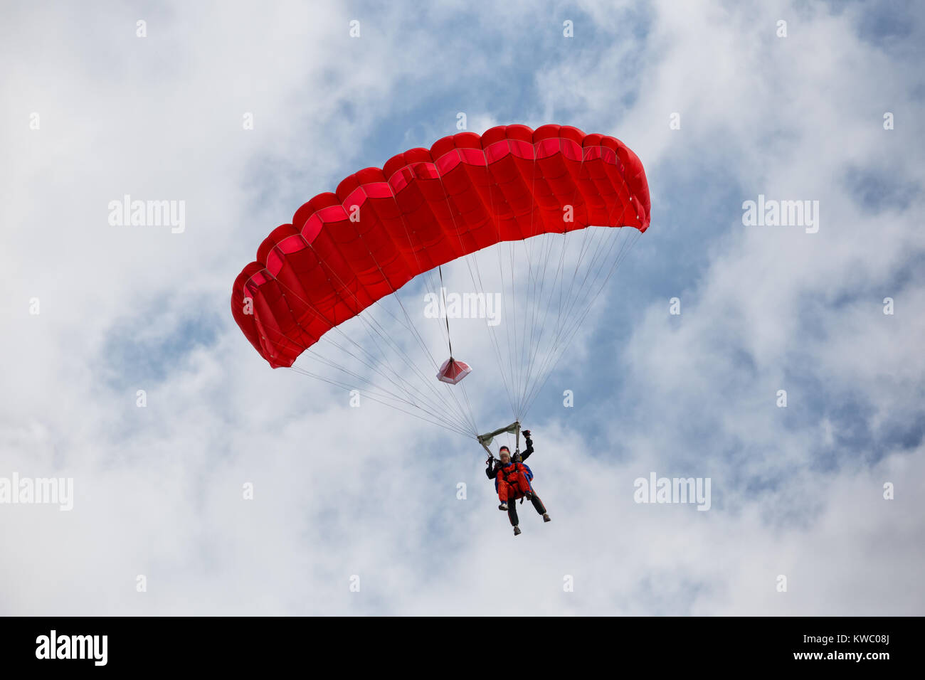 Parachuter scendendo con un paracadute rosso Foto Stock