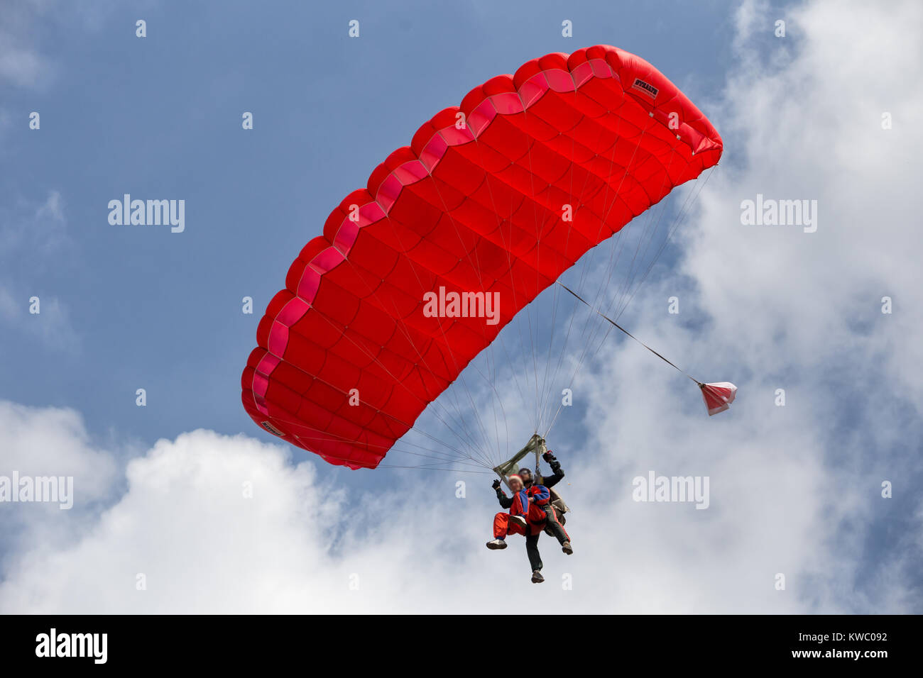 I paracadutisti in tandem si scende su un paracadute rosso Foto Stock