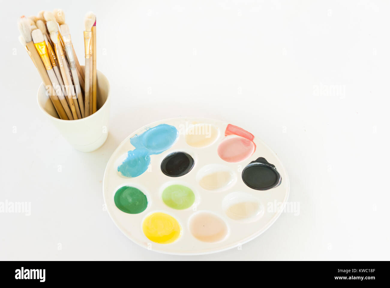 La colorata acqua piastra di colore con i pennelli su sfondo bianco Foto Stock