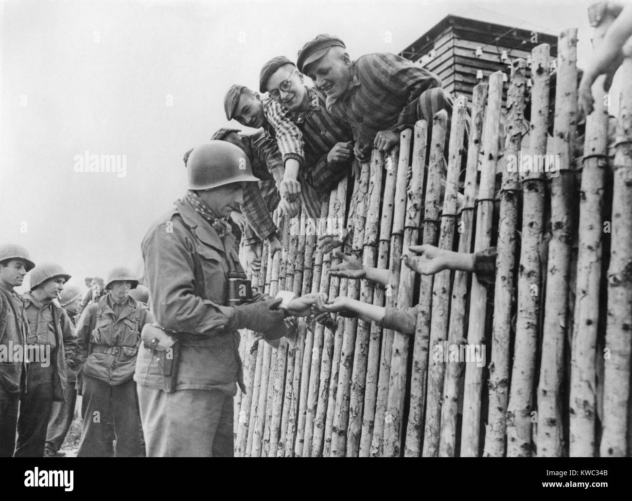 GI del settimo US Army dà il suo ultimo sigarette a liberati i prigionieri di Dachau dietro un stockade. Aprile 29, 1945, guerra mondiale 2 (BSLOC 2015 13 21) Foto Stock