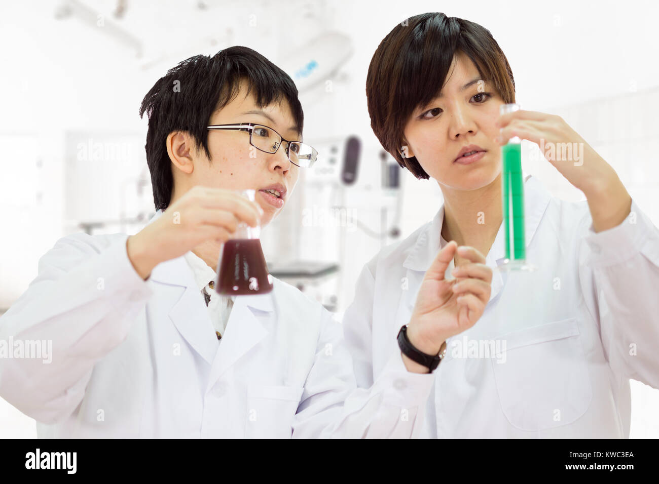Asia femmina gli scienziati americani in un laboratorio di ispezionare i prodotti chimici nel tubo Foto Stock
