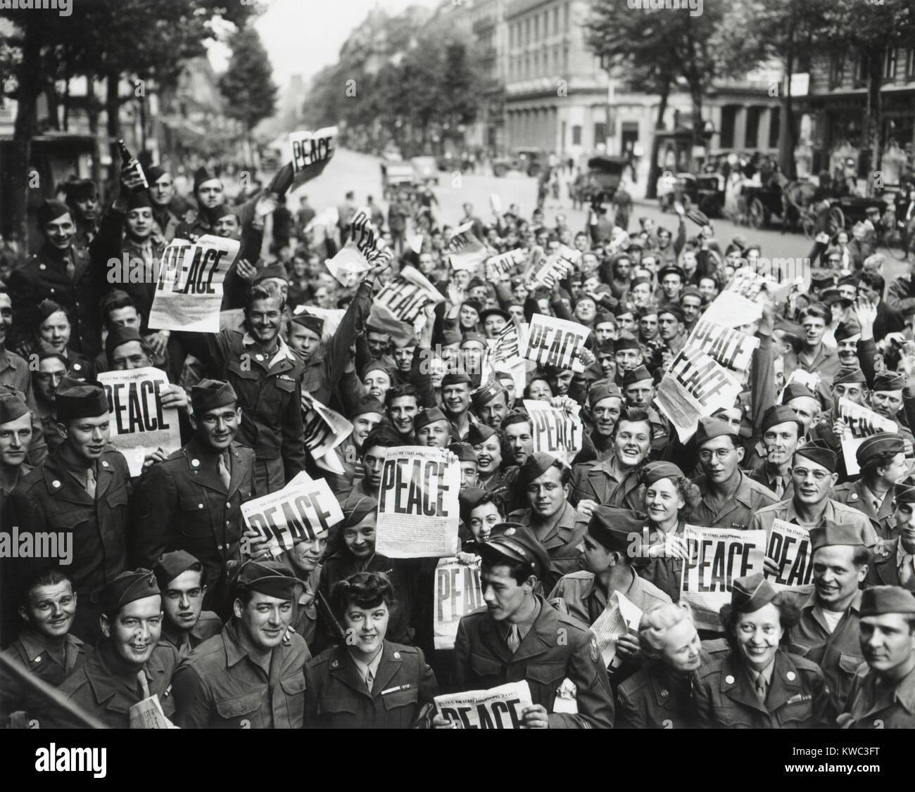 V-j giorno a Parigi, Francia. GI e onda WACs STELLE E STRISCE headline, pace. Agosto 14, 1945. (BSLOC 2015 13 87) Foto Stock