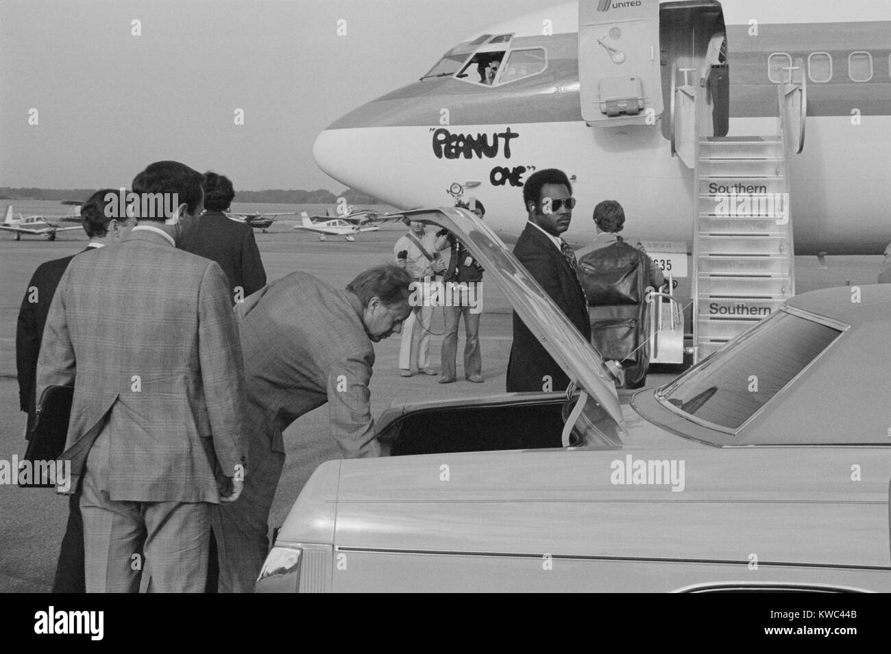 Jimmy Carter per recuperare il suo bagaglio da una vettura prima di salire a bordo il comando 'arachidi un' aereo di campagna. Carter è apparso come un uomo del popolo da trasportare il suo bagaglio quando la campagna elettorale. Sett. 13, 1976. (BSLOC 2015 14 68) Foto Stock