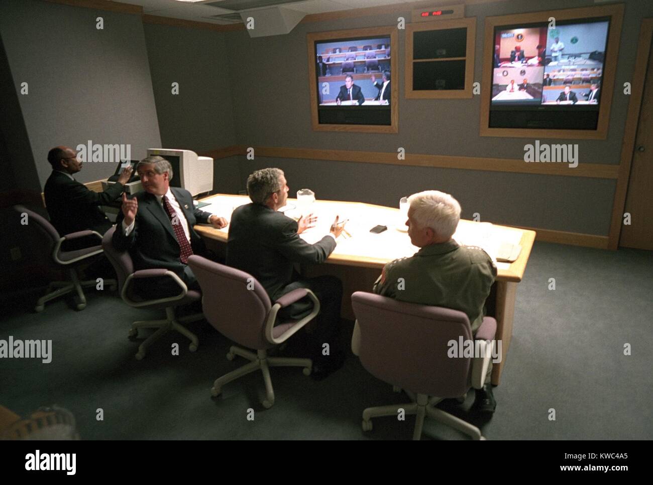 Il Presidente George W Bush in un video multischermo conferenza presso Offutt Air Force Base, Sett. 11, 2001. Egli si è incontrato con il Consiglio nazionale di sicurezza in una teleconferenza attraverso gli Stati Uniti STRATCOM bunker. Arrivò da Sarasota a 2:50 PM e sinistra per Washington, D.C. al 4:26 PM. Seduta accanto a Bush sono il capo del personale della Casa Bianca, Andy Card (sinistra) e ADM. Richard Mies. (BSLOC 2015 2 134) Foto Stock