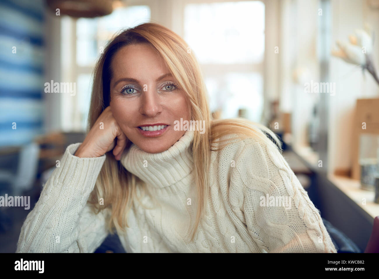 Ritratto di una bella donna bionda con i capelli lunghi e gli occhi blu guardando la fotocamera in luoghi chiusi rilassata Foto Stock