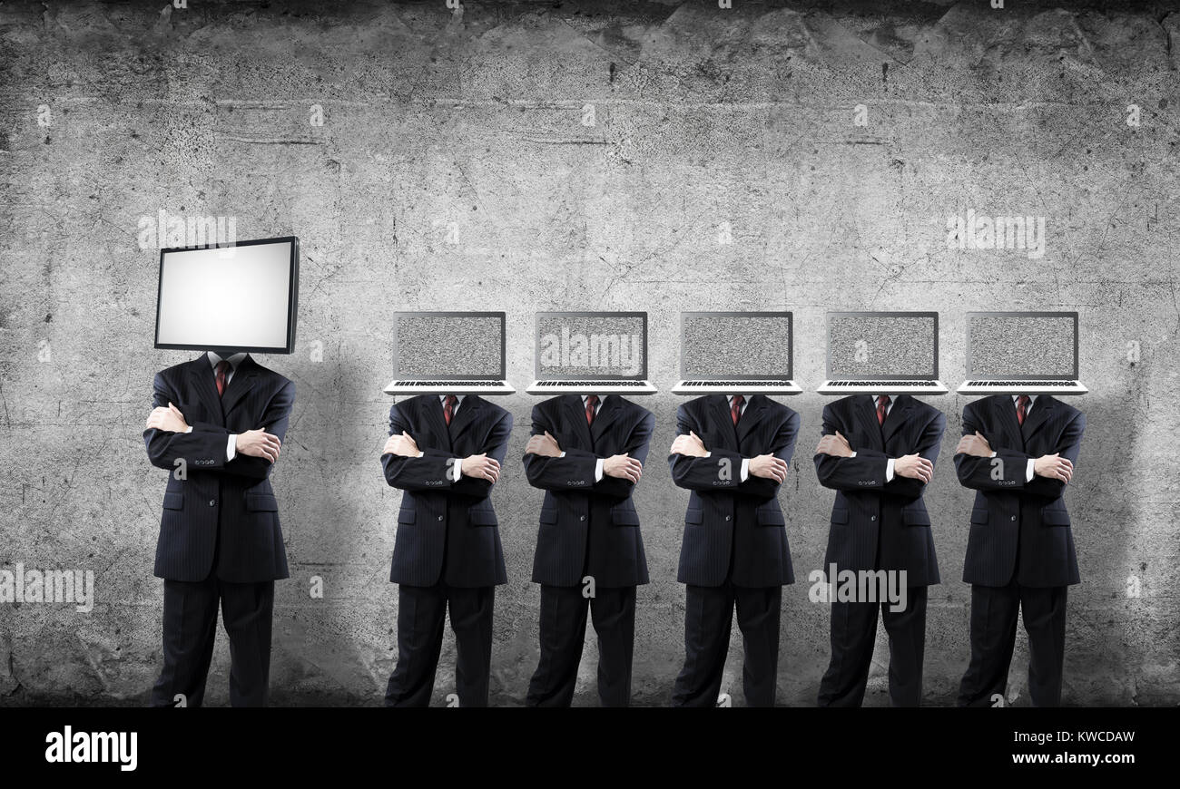 Uomini d'affari in giacca con i laptop invece dei loro capi mantenendo le braccia incrociate mentre in piedi in una riga e uno a testa con TV in camera a vuoto contro Foto Stock