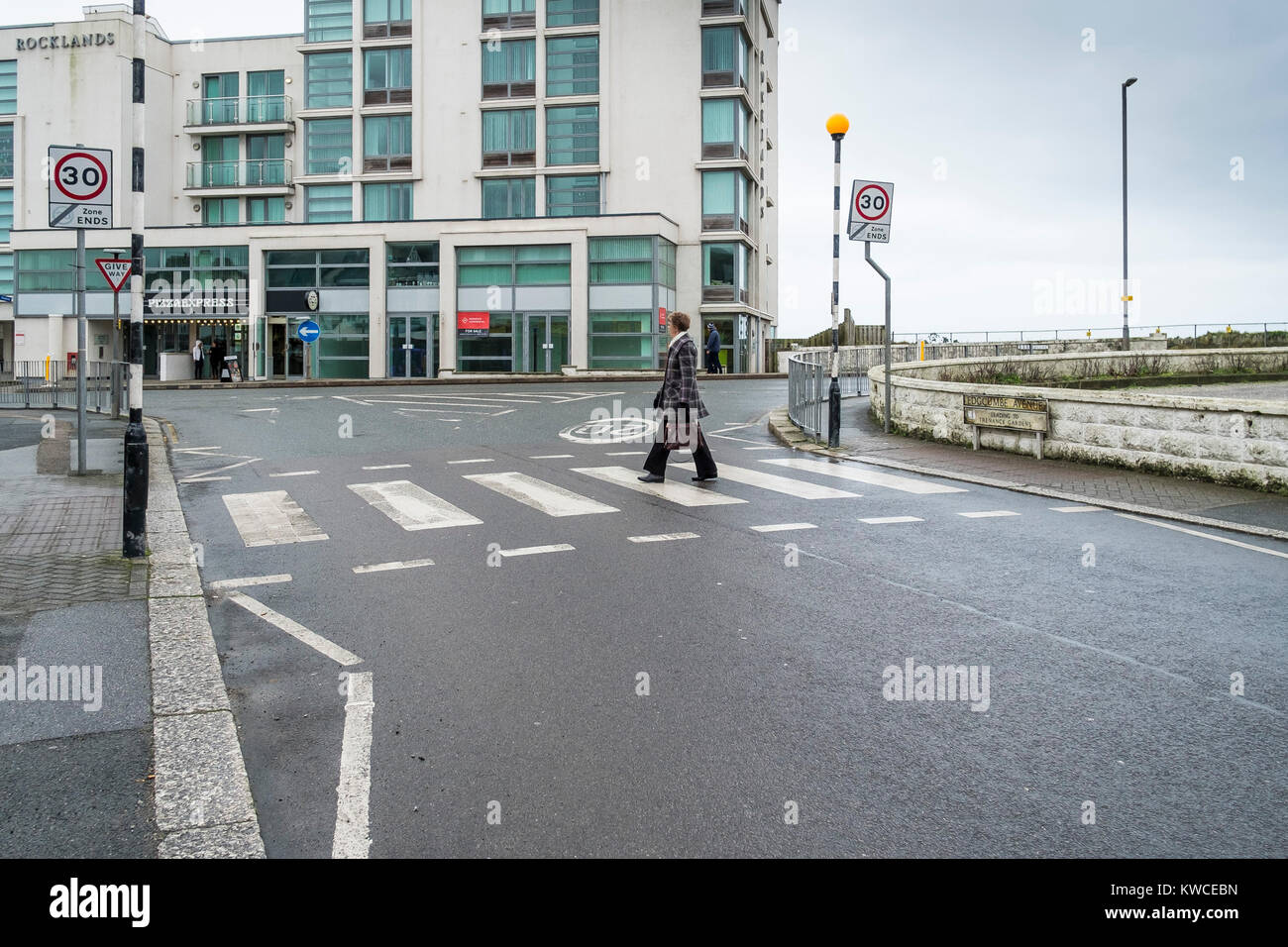 Newquay scena di strada - una donna a piedi attraverso una zebra crossing nella tranquilla stagione in Newquay centro città. Foto Stock