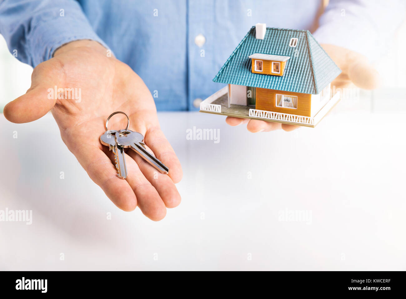 Agente immobiliare con modello di casa e chiavi in mano Foto Stock
