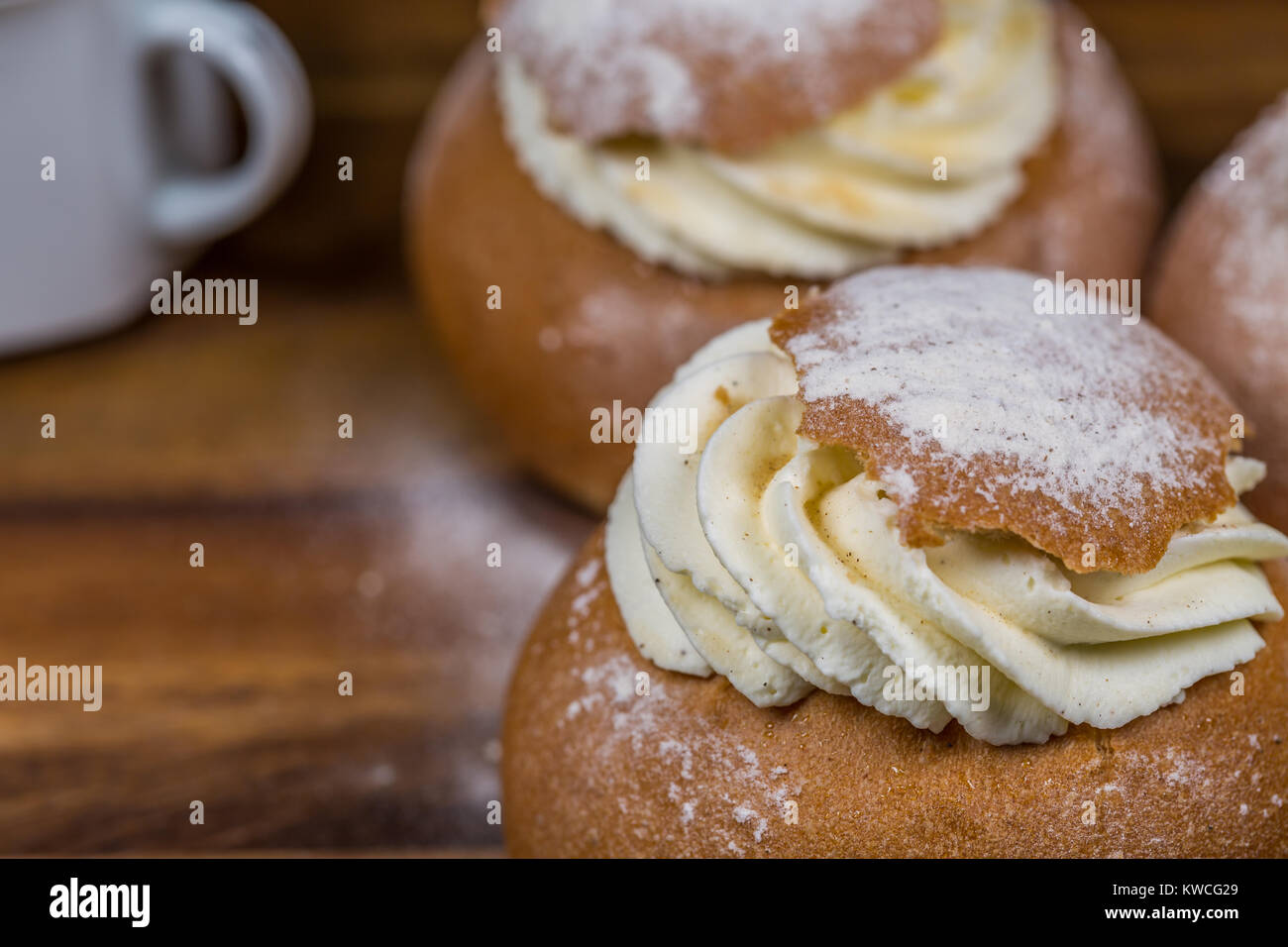 Cup e torte Semla coperti dalla polvere di zucchero sul tavolo di legno Foto Stock