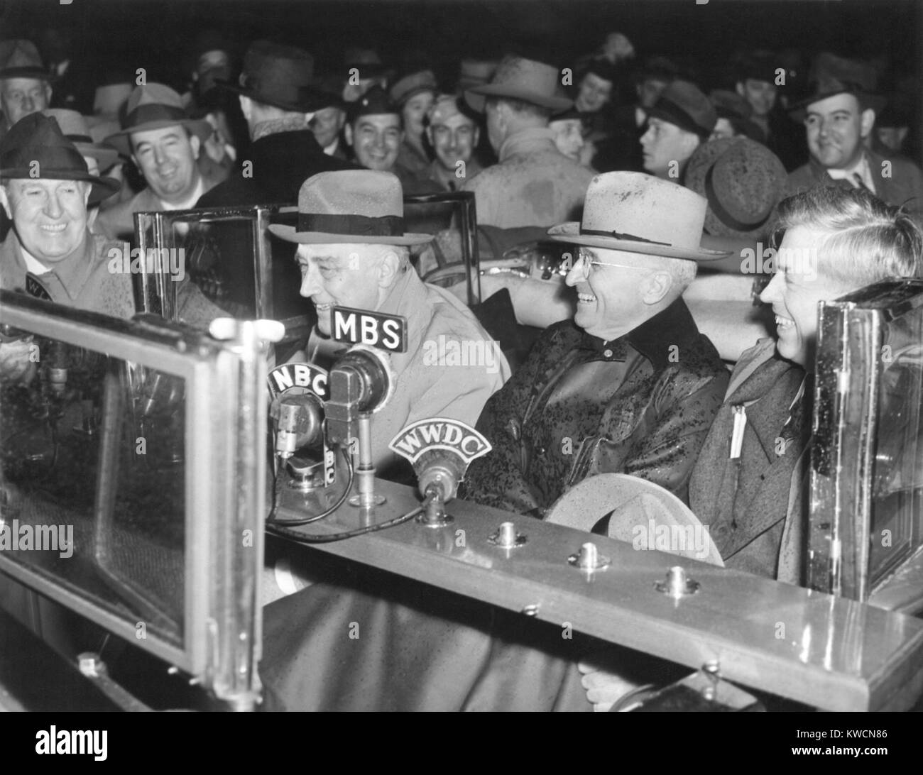 Il presidente Franklin Roosevelt parlando nel microfono radio dalla sua vettura aperta sotto la pioggia. VP-elect Harry Truman si siede tra FDR e l'uscita VP Henry Wallace. Novembre 10, 1944. - (BSLOC 2014 15 13) Foto Stock