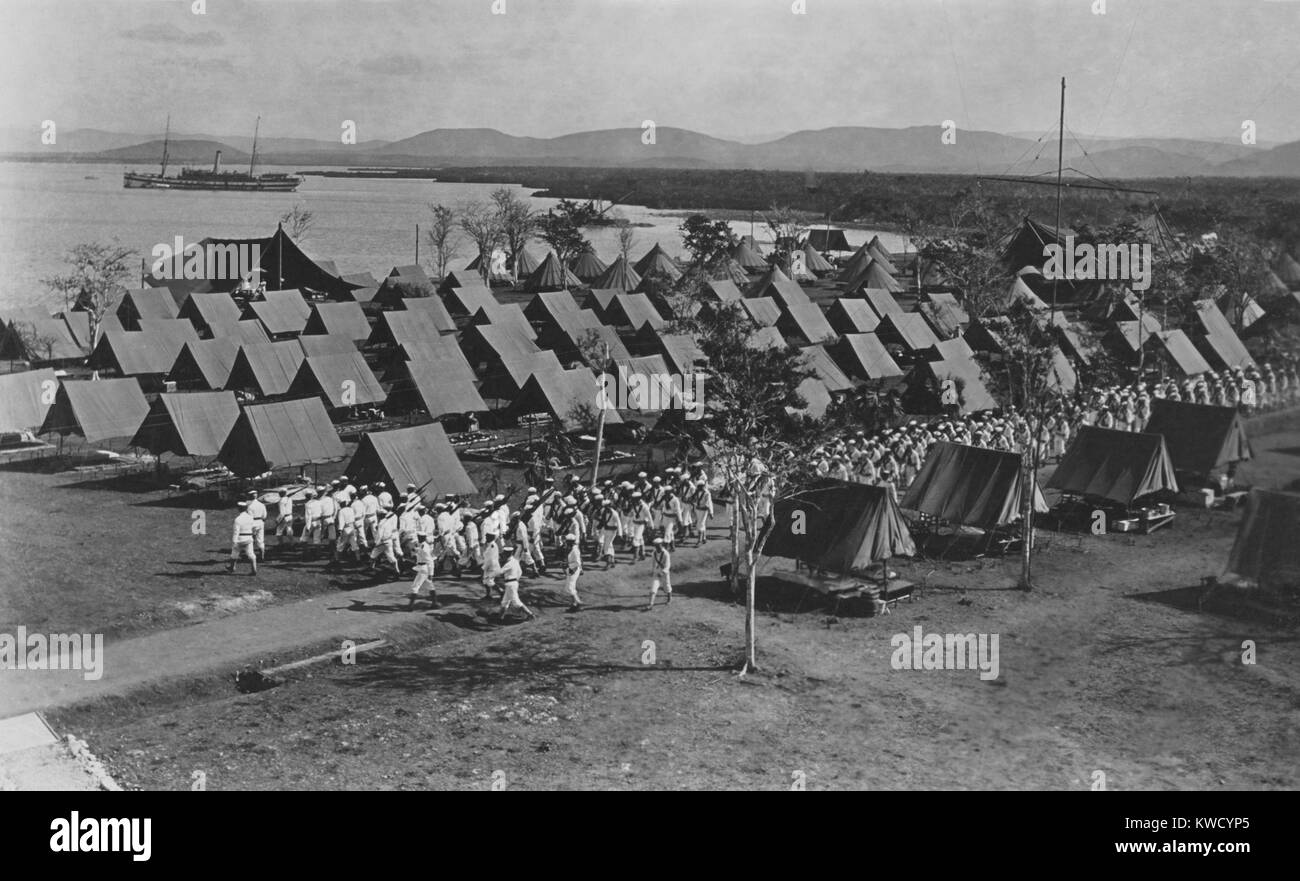 Atlantico marinai della flotta marciando attraverso un campo in tenda a Guantánamo Bay a Cuba, 1909. Essi scortecciato dall'USS SOLACE visto in background (BSLOC 2017 2 80) Foto Stock