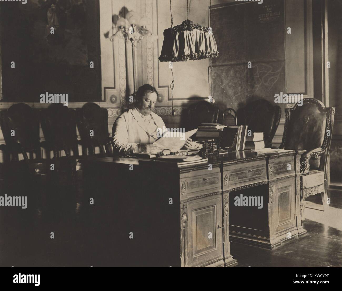 In futuro Presidente, William H. Taft, come Governatore Generale delle Filippine, 1901-1903. Egli legge un giornale alla sua scrivania con una mappa di Manila sulla parete per ufficio (BSLOC 2017 2 93) Foto Stock