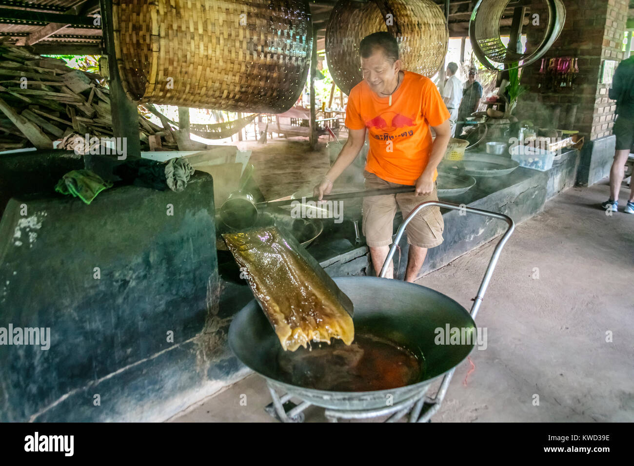 Lavoratore tailandese rimozione evaporato il cocco Zucchero Sciroppo di sap da riscaldata vaschette a Coconut piantagione di zucchero, Tambon Kradangnga, Samut Songkhram, Thailandia. Foto Stock