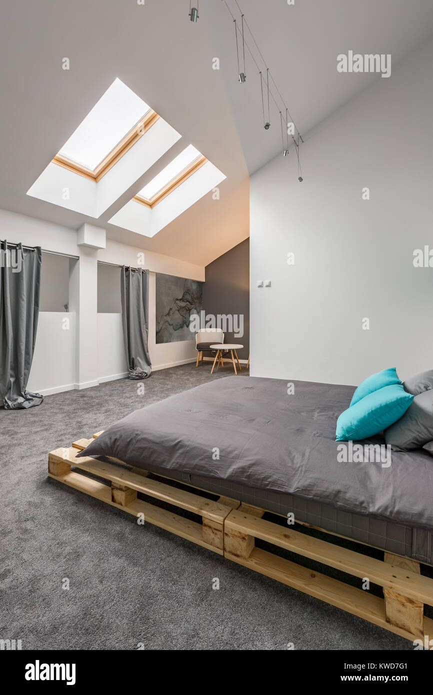 Mansarda Camera da letto con letto di pallet e pavimento in grigio Foto Stock