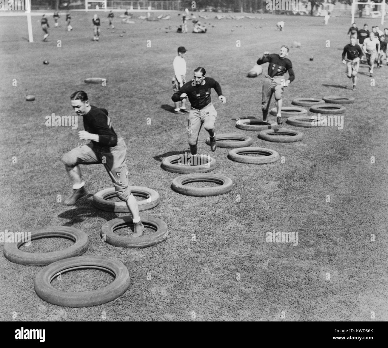 Punto ad ovest della squadra di calcio di alta stepping attraverso un labirinto di pneumatici durante il loro primo pratica. 1920s. (BSLOC 2015 17 127) Foto Stock