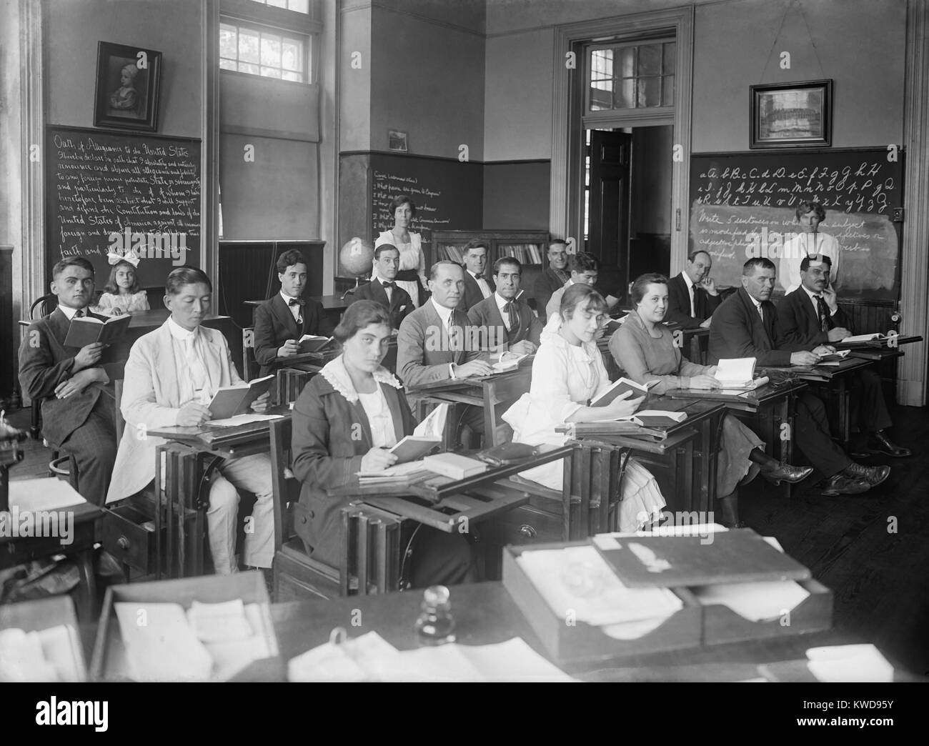 Gli uomini e le donne in un americanization classe nella zona di Washington D.C., c. 1920. Composta per la maggior parte degli europei con una est uomo asiatico, la classe ha incontrato in una scuola locale. Un giuramento di fedeltà' è scritto sulla lavagna a sinistra (BSLOC 2016 8 80) Foto Stock