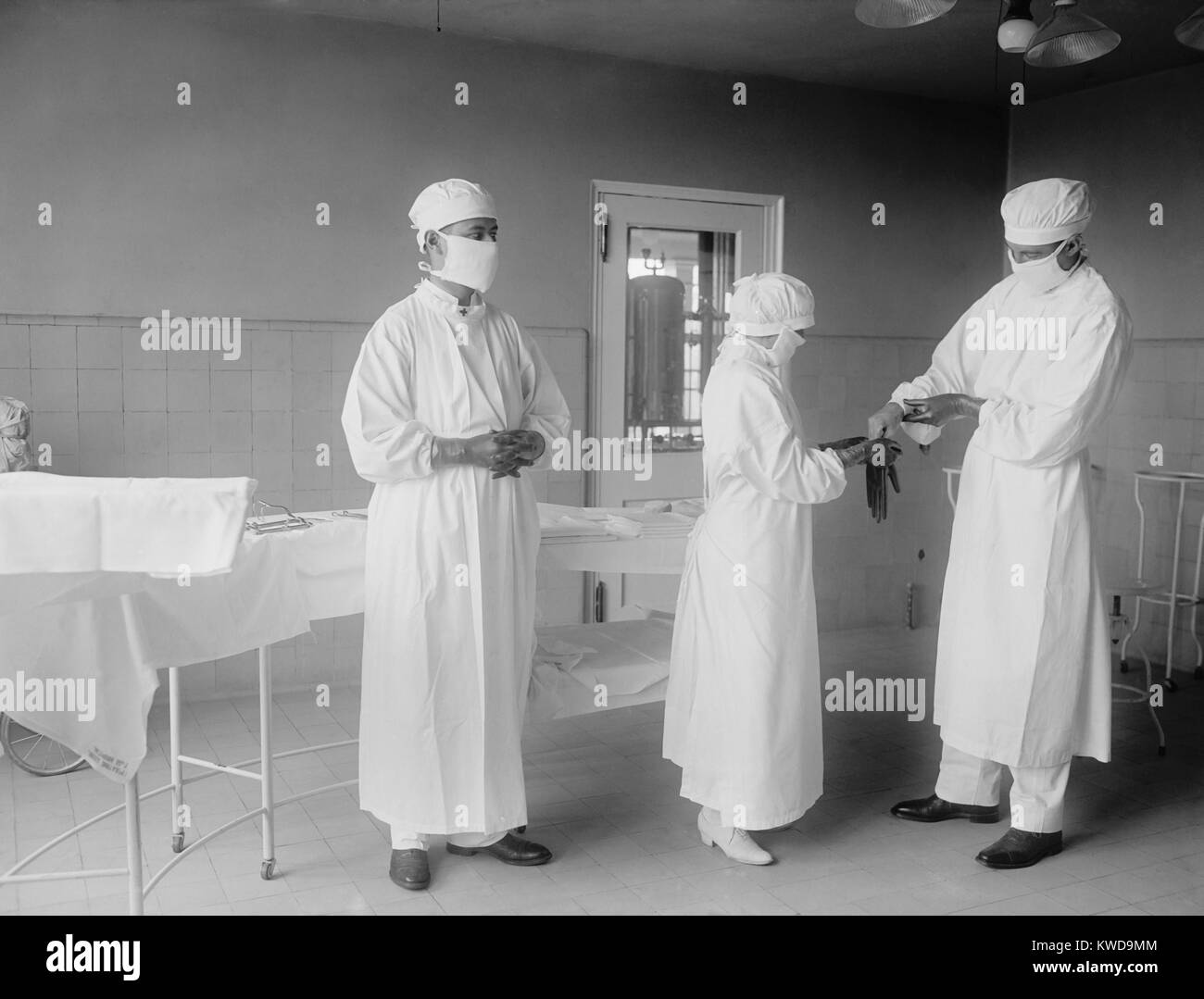 Infermiere chirurgico assiste i chirurghi in guanti di gomma prima di un'operazione. 1922 in un ospedale di Washington, D.C. (BSLOC 2016 10 32) Foto Stock