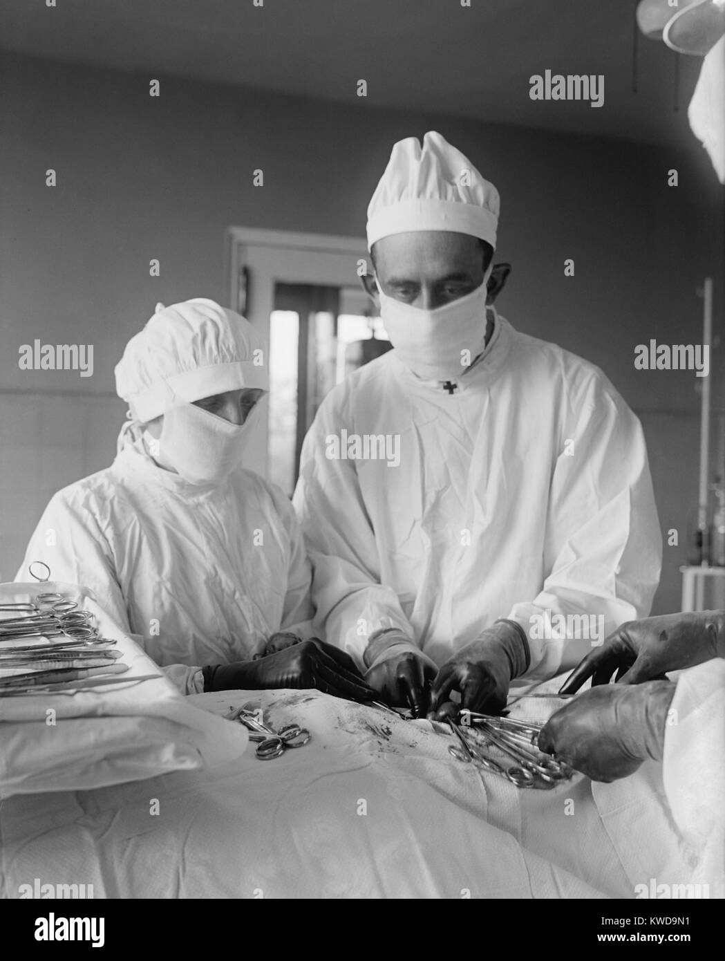 Assistere il chirurgo e infermiere chirurgico con strumenti specializzati durante un'operazione. Il sangue può essere visto nella zona chirurgica. 1922 in un ospedale di Washington, D.C. (BSLOC 2016 10 35) Foto Stock