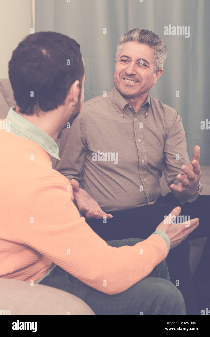 Coppia padre e figlio sono una cordiale conversazione seduti a casa sul divano Foto Stock