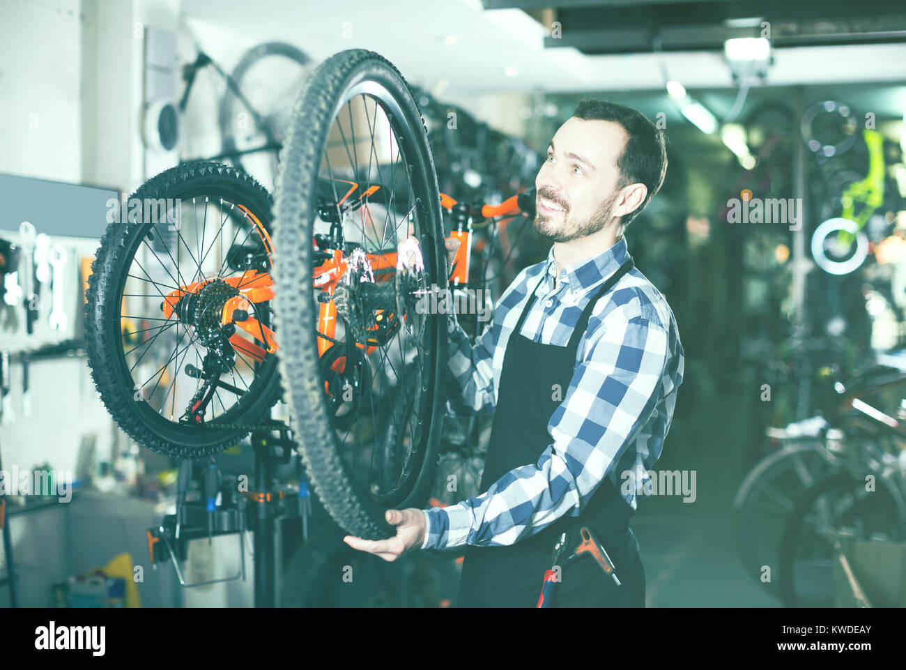 Uomo sorridente master stabilisce una ruota di bicicletta nel suo laboratorio Foto Stock