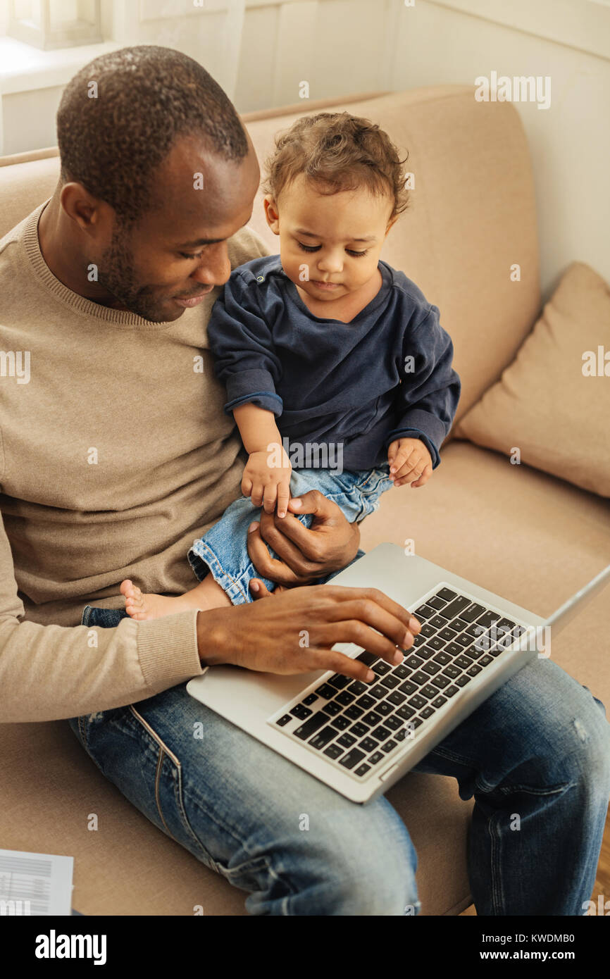 Felice papà lavora e il servizio di baby-sitter Foto Stock