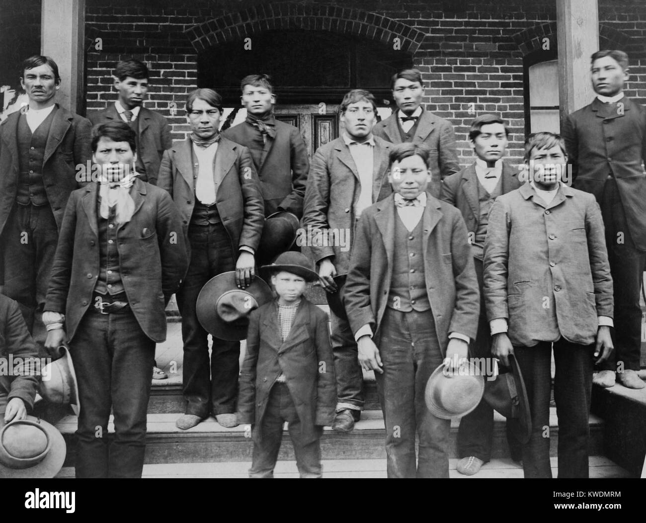 Native American giovani uomini e un ragazzo poste sui gradini di Carlisle Indian School, c. 1890. Scuole indiane bambini separati dalle loro famiglie e alienato dal Native American cultura, lingua, religione e anche sostituito i loro nomi indiani. Carlisle era il modello per 26 Ufficio di affari indiani e religiosi privati Collegi (BSLOC 2017 18 41) Foto Stock