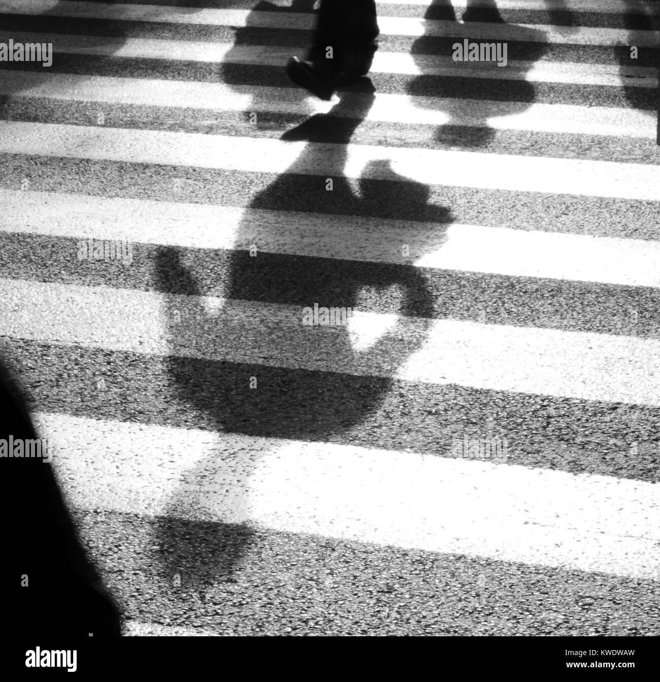 Ombre sfocati di pedoni che attraversano la strada a zebra bivio , in bianco e nero Foto Stock