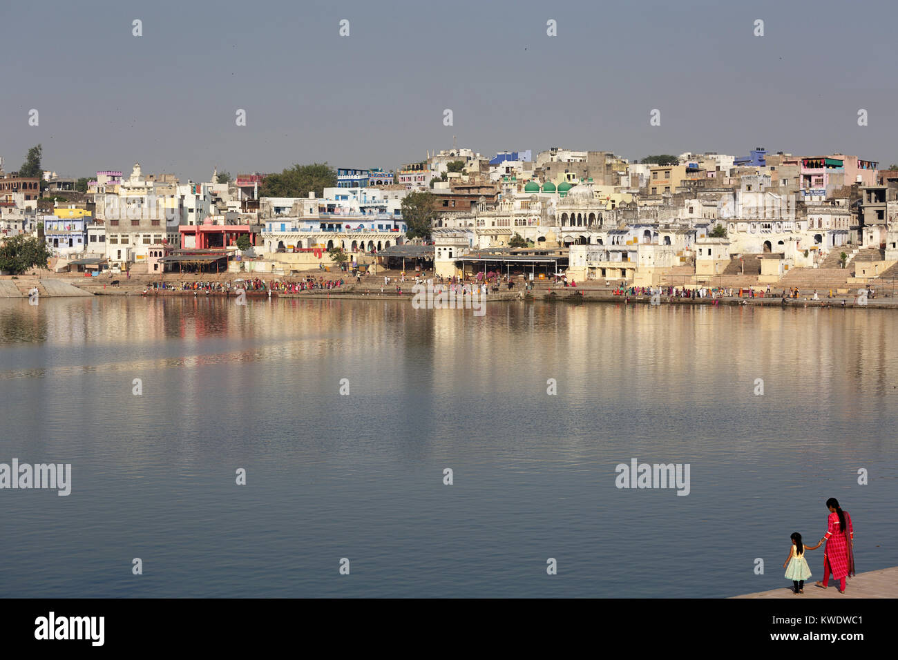 Madre e figlia in sari sulla banca del lago santo a Pushkar, pellegrini Indù prendendo un bagno rituale ion l'altro lato, il Rajasthan, India. Foto Stock