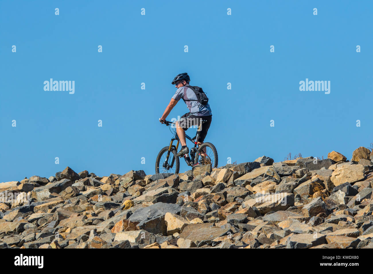Mountain bike rider su un sentiero con un vivid blue sky dietro Foto Stock