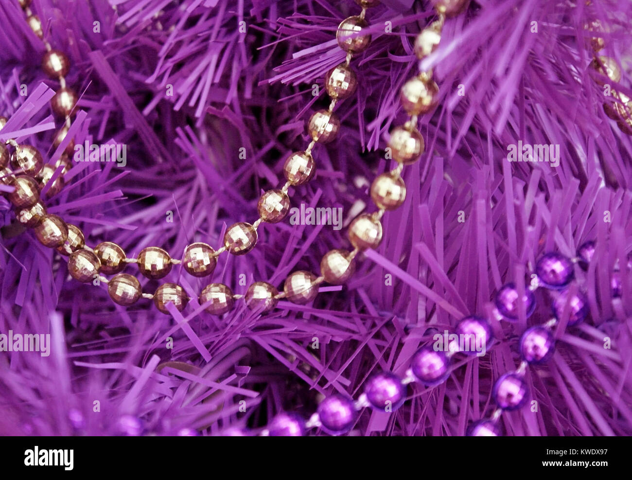 Oro e porpora cordone ghirlande infilate su un viola albero artificiale Foto Stock