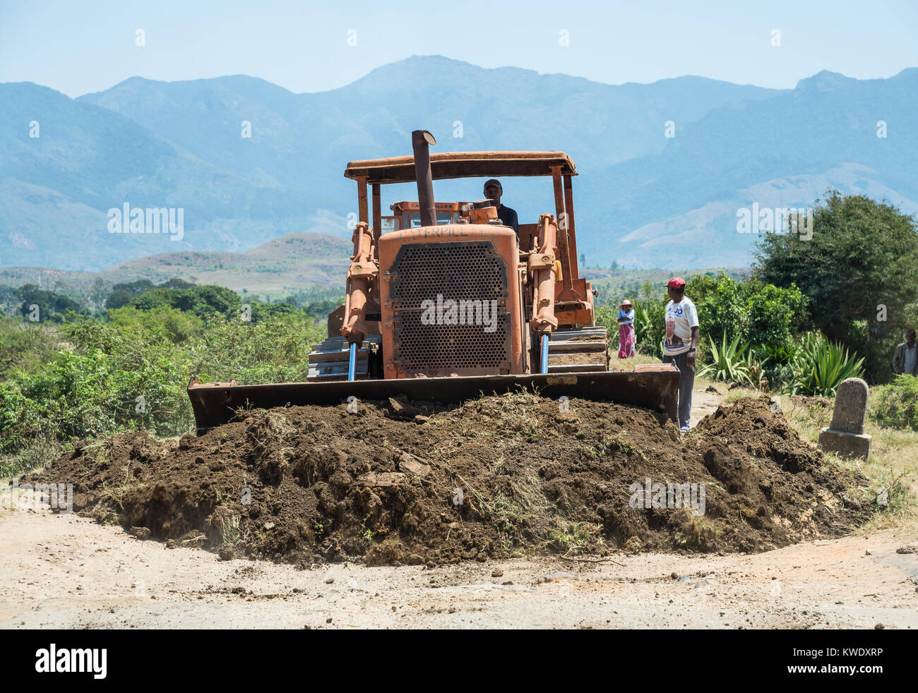 Un bulldozer spingere lo sporco sulla strada per la riparazione di buche. Madagascar, Africa. Foto Stock