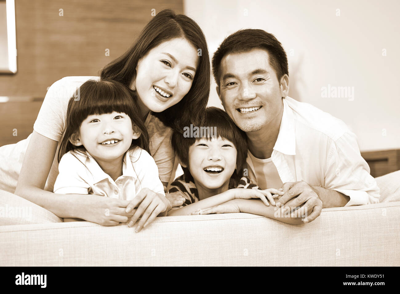 Ritratto di una famiglia asiatica con due bambini, felice e sorridente, in bianco e nero seppia. Foto Stock