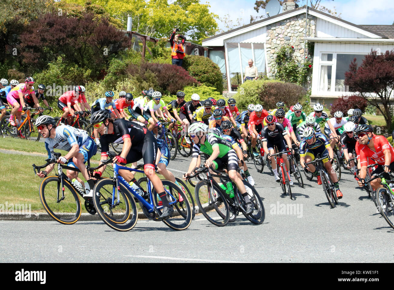 Tour del Southland cycle race passando attraverso Manapouri nell Isola del Sud, Nuova Zelanda mostra impaccato peleton esegue una curva. Foto Stock