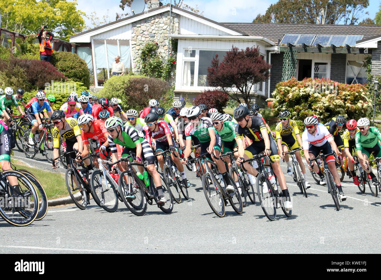 Tour del Southland cycle race passando attraverso Manapouri nell Isola del Sud, Nuova Zelanda mostra impaccato peleton esegue una curva. Foto Stock