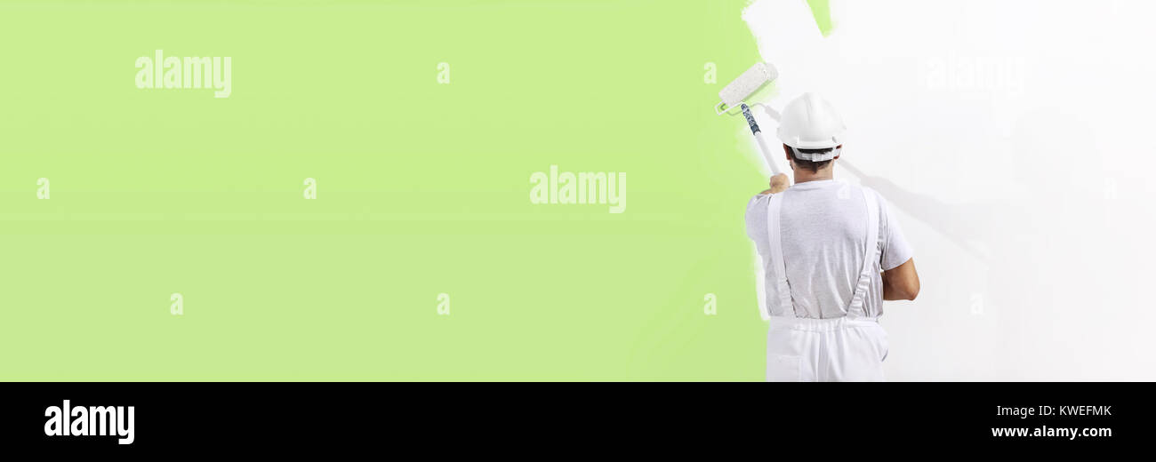 Pittore uomo al lavoro con un rullo di vernice, muro dipinto di colore verde concetto ecologico, web modello di pagina di intestazione Foto Stock