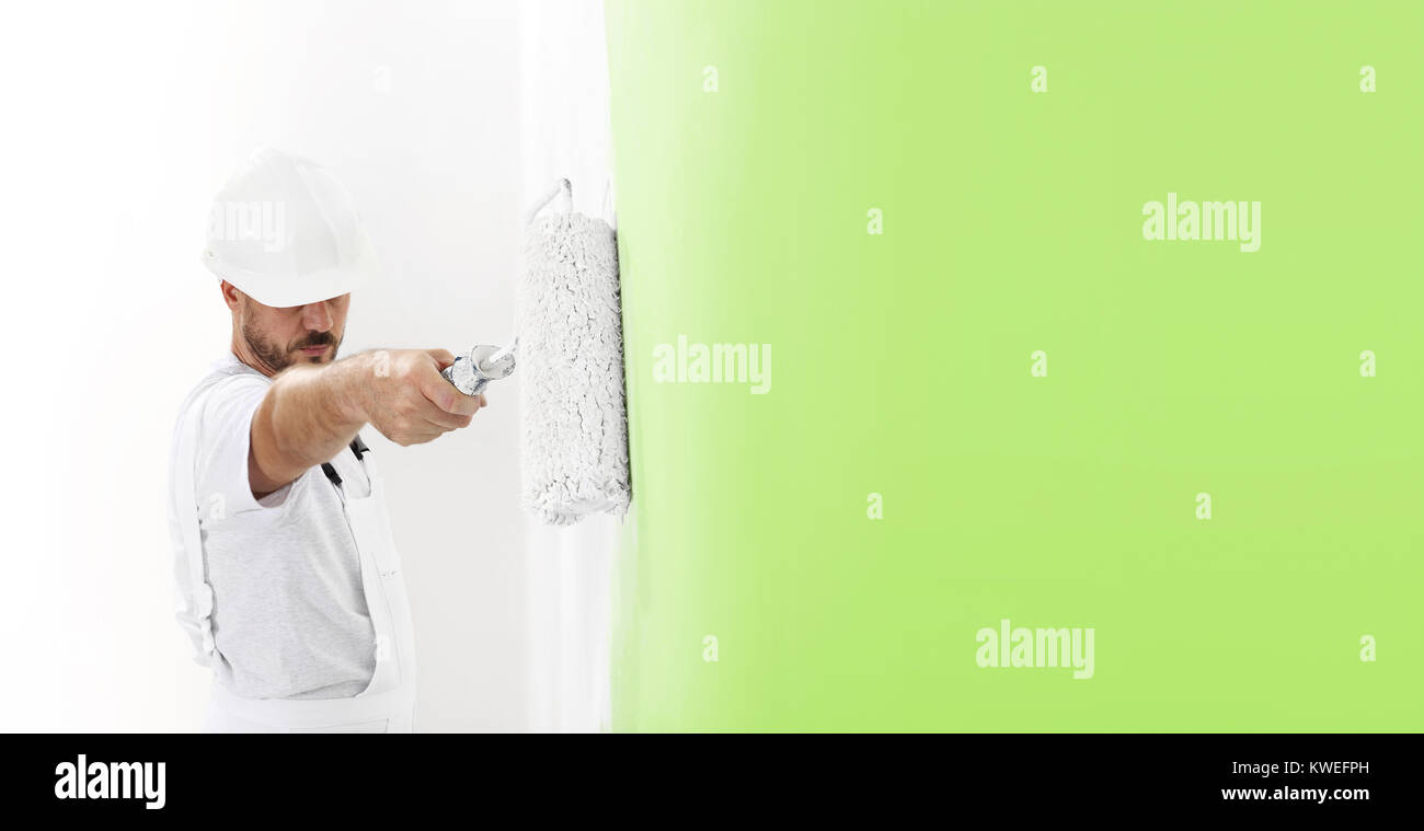 Pittore uomo al lavoro con un rullo di vernice, muro dipinto di colore verde concetto ecologico, web modello di pagina di intestazione Foto Stock
