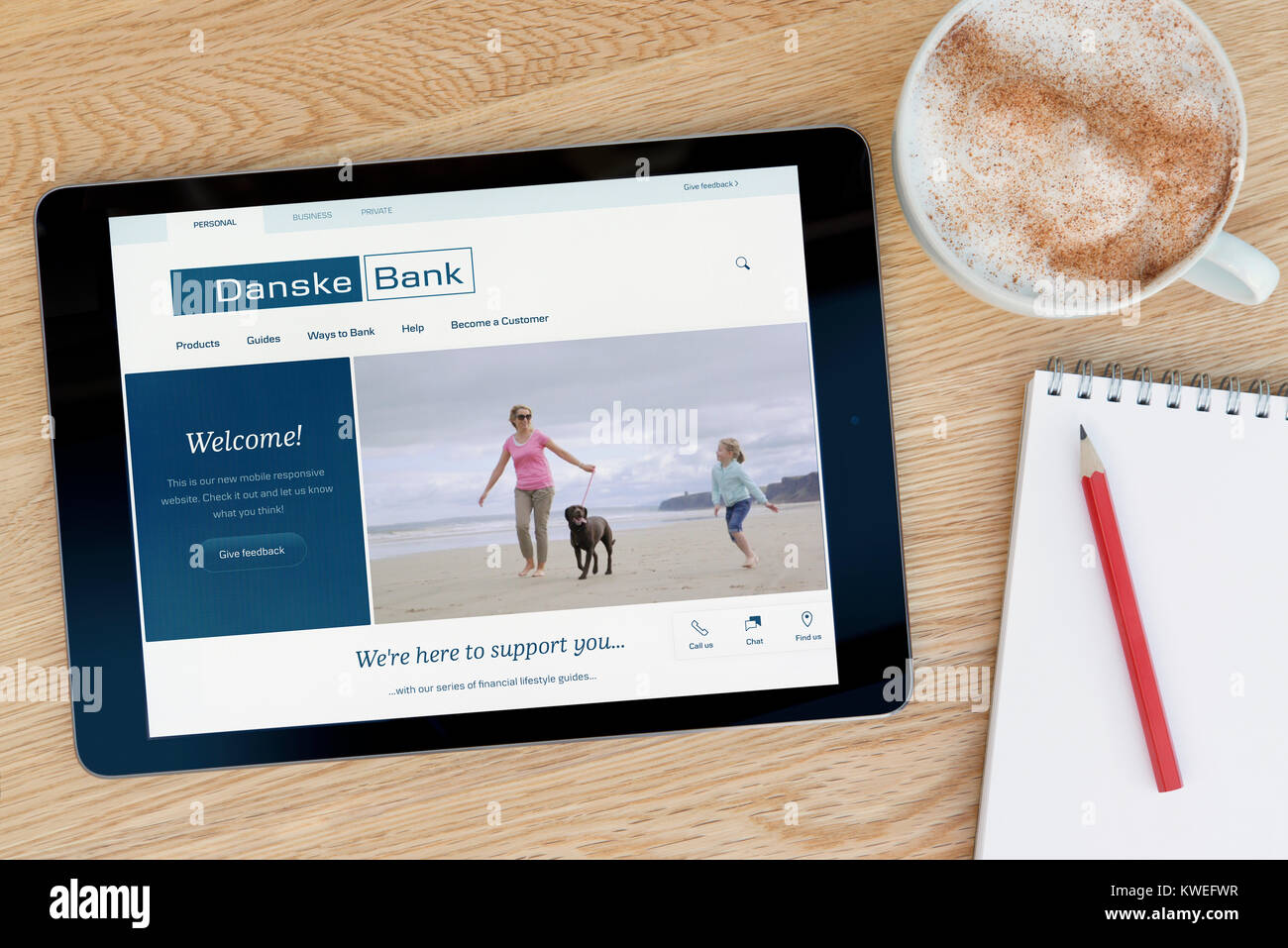 La Danske Bank sito web su un iPad dispositivo tablet, appoggiato su un tavolo di legno accanto a un blocco note, matita e tazza di caffè (editoriale solo) Foto Stock