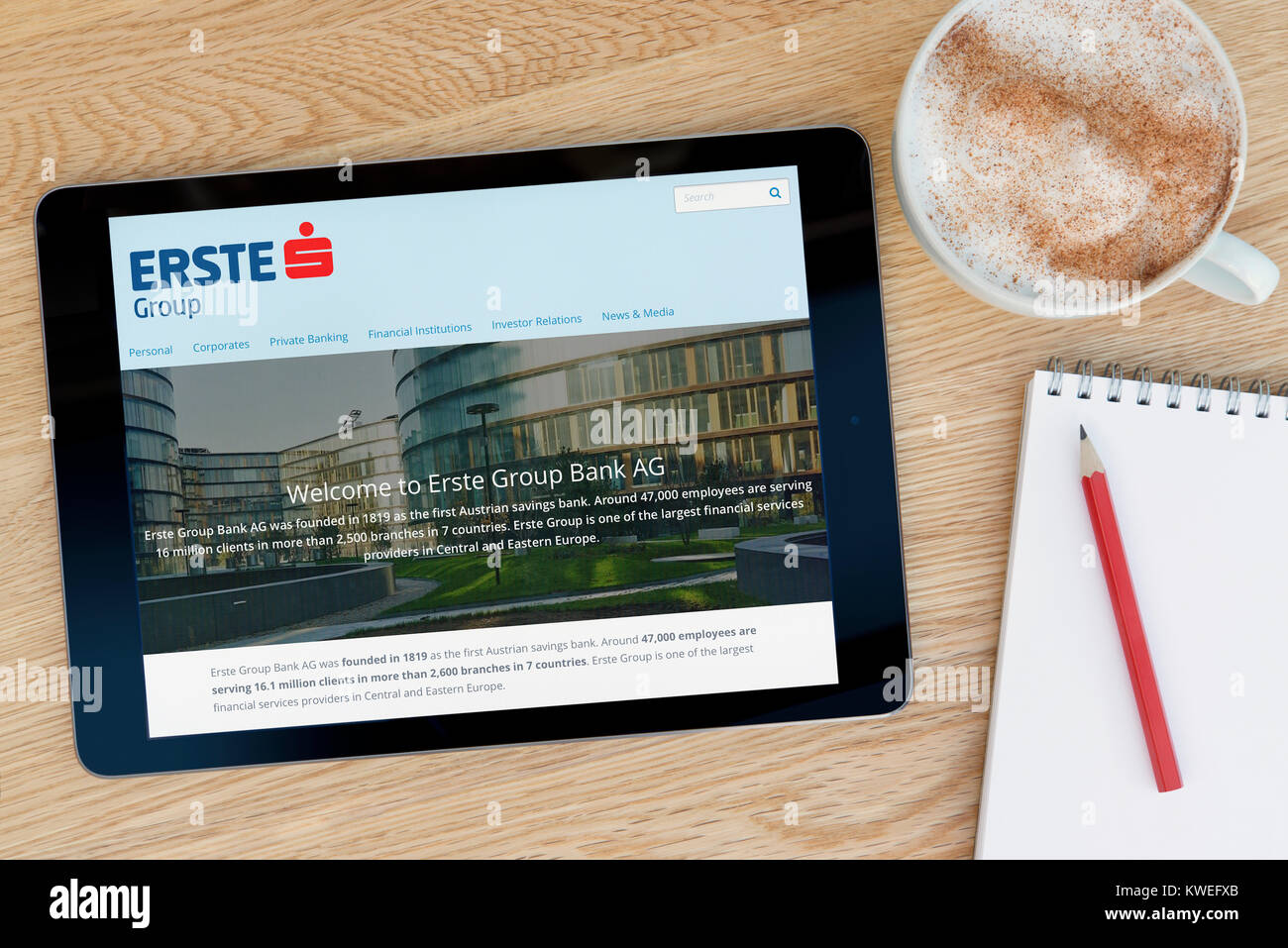 La Erste Group sito web su un iPad dispositivo tablet, appoggiato su un tavolo di legno accanto a un blocco note, matita e tazza di caffè (editoriale solo) Foto Stock
