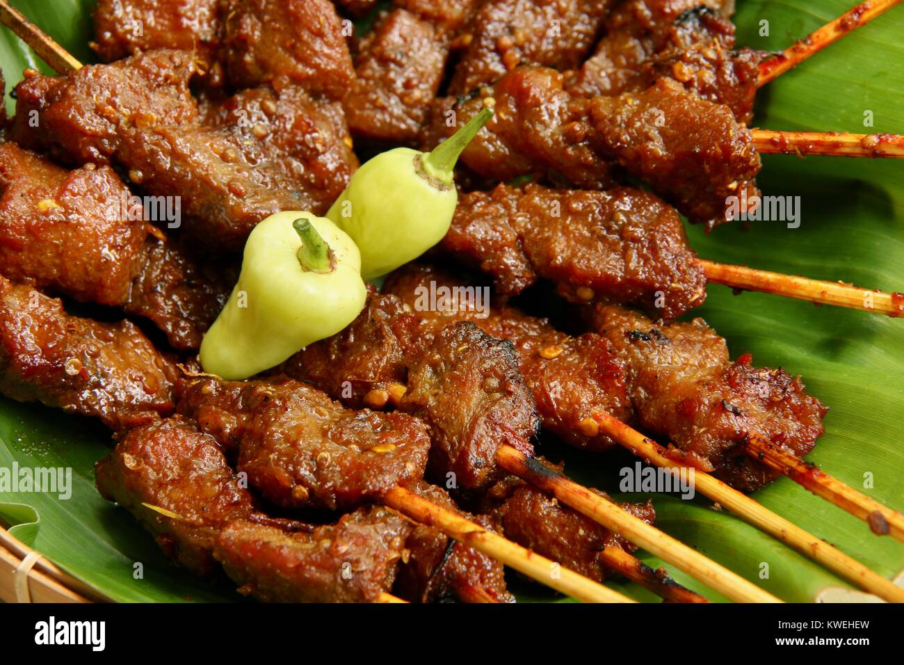 Sate Babi Bali. Balinese di maiale piccante saté; disposti su foglia di banano e guarnita con peperoncini verdi. Foto Stock