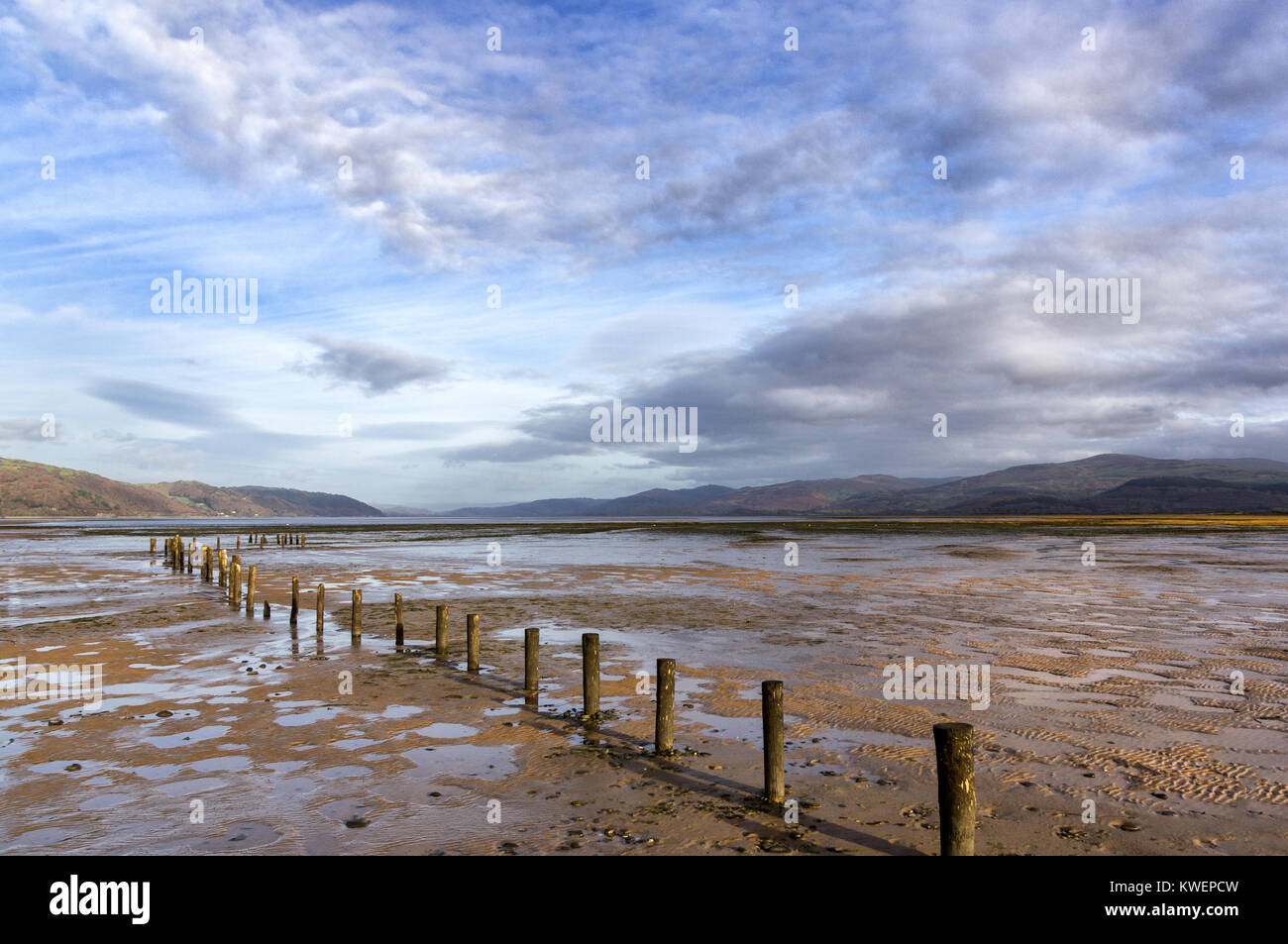 Sunny autunno luce a Ynyslas riserva naturale, Dovey estuario, in Galles a bassa marea, eroso recinzione in primo piano e le montagne Cambriano in background Foto Stock